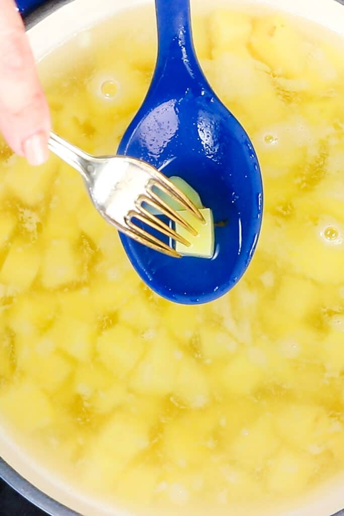 a fork going into a potato cub in a spoon