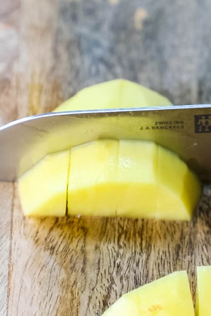 a potato being cut into cubes