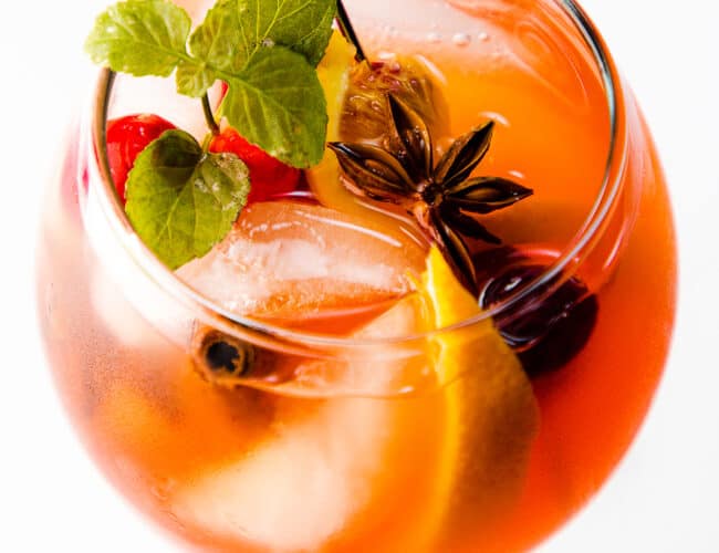 A glass of holiday sangria rarnished with fruit and mint