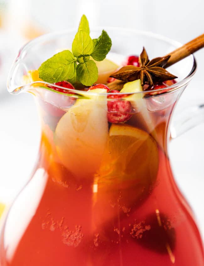 a pitcher Holiday Sangria garnished with fruit and herbs