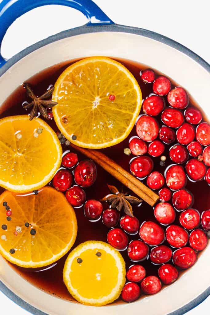 a pot with cranberry juice, fresh cranberries, cinnamon sticks, and orange slices