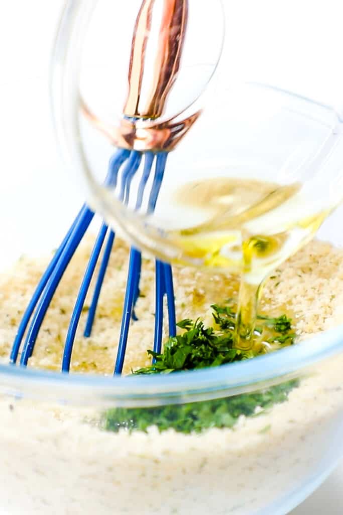 olive oil being poured into the breadcrumb mixture