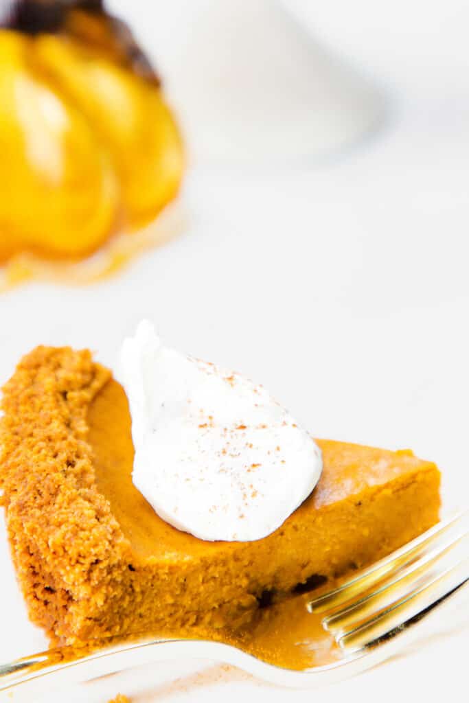a whipped cream topped slice of apple pie on a plate with a fork