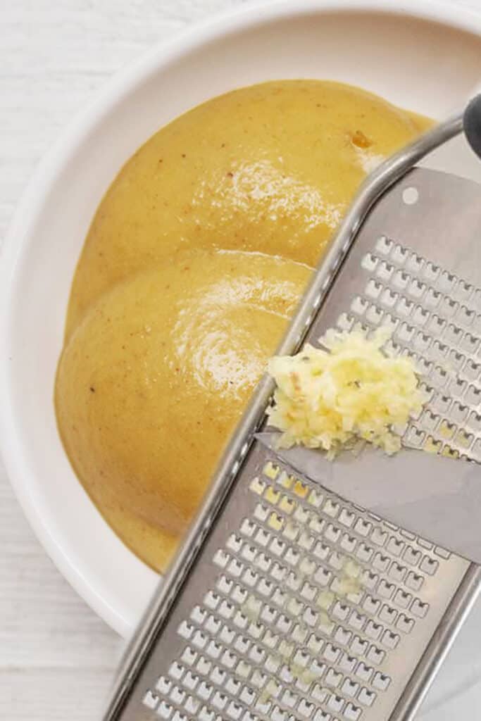 the garlic being added to the bowl with the mustard