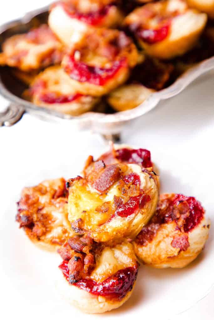 a plate of 4 brie bites with cranbery sauce and bacon
