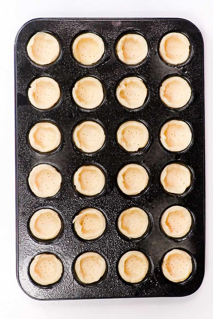 dough pressed into sections of a mini muffin pan