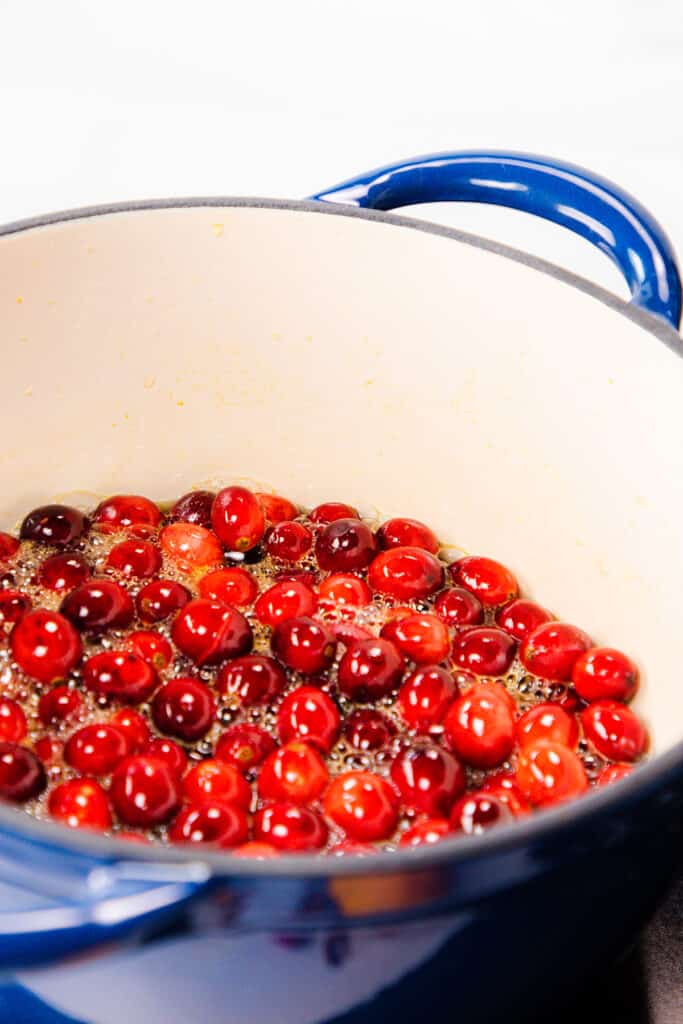cranberries cooking in the sugar mixture in a blue pot