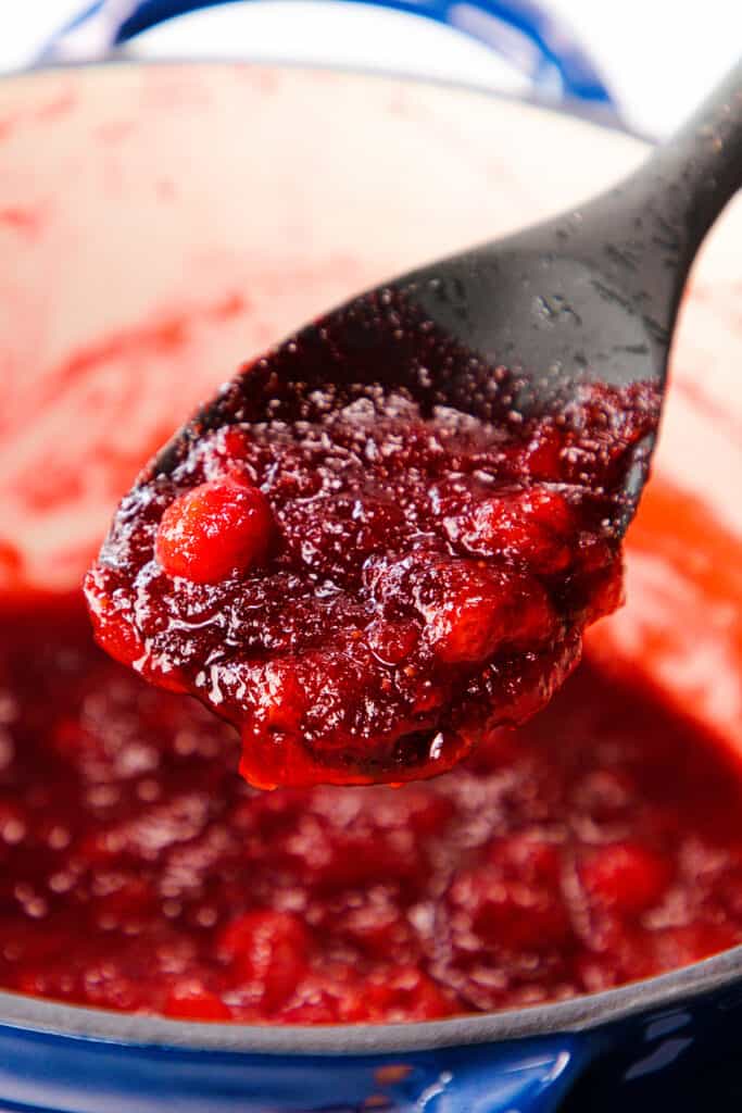 cooked cranberry sauce in a spoon over a pot