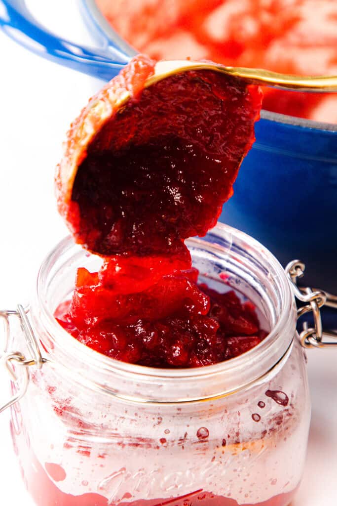the Homemade Fresh Cranberry Sauce being spooned into a jar