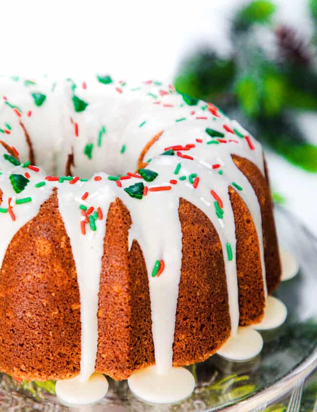 a close up image of an eggnog bundt cake topped with glaze and holiday sprinkles