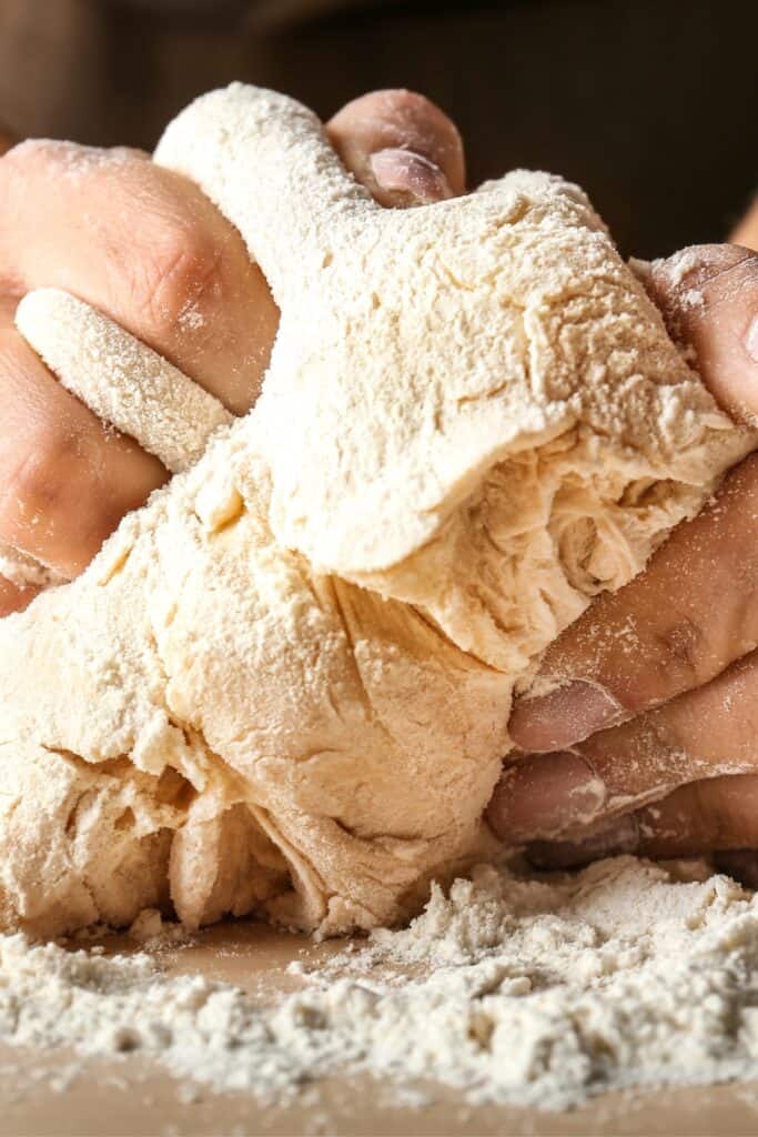 hands kneading dough in flour