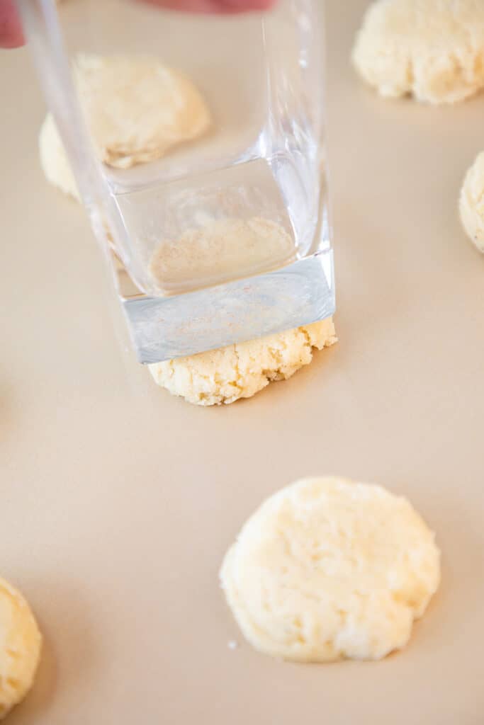 a drinking glass pressing the dough ball onto a cookie sheet