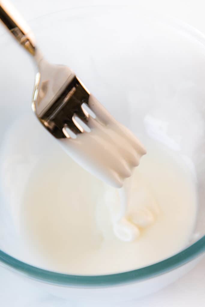 icing flowing off a fork into a bowl