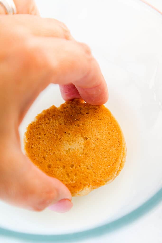 a Soft Sugar Cookie being dipped into a bowl of icing