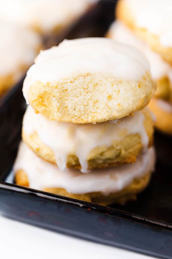 a stack of Soft sugar cookies with icing. A is bite missing from the top cookie