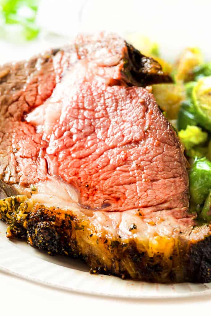 a close up image of a slice of ribeye roast beef on a plate with Brussels Sprouts