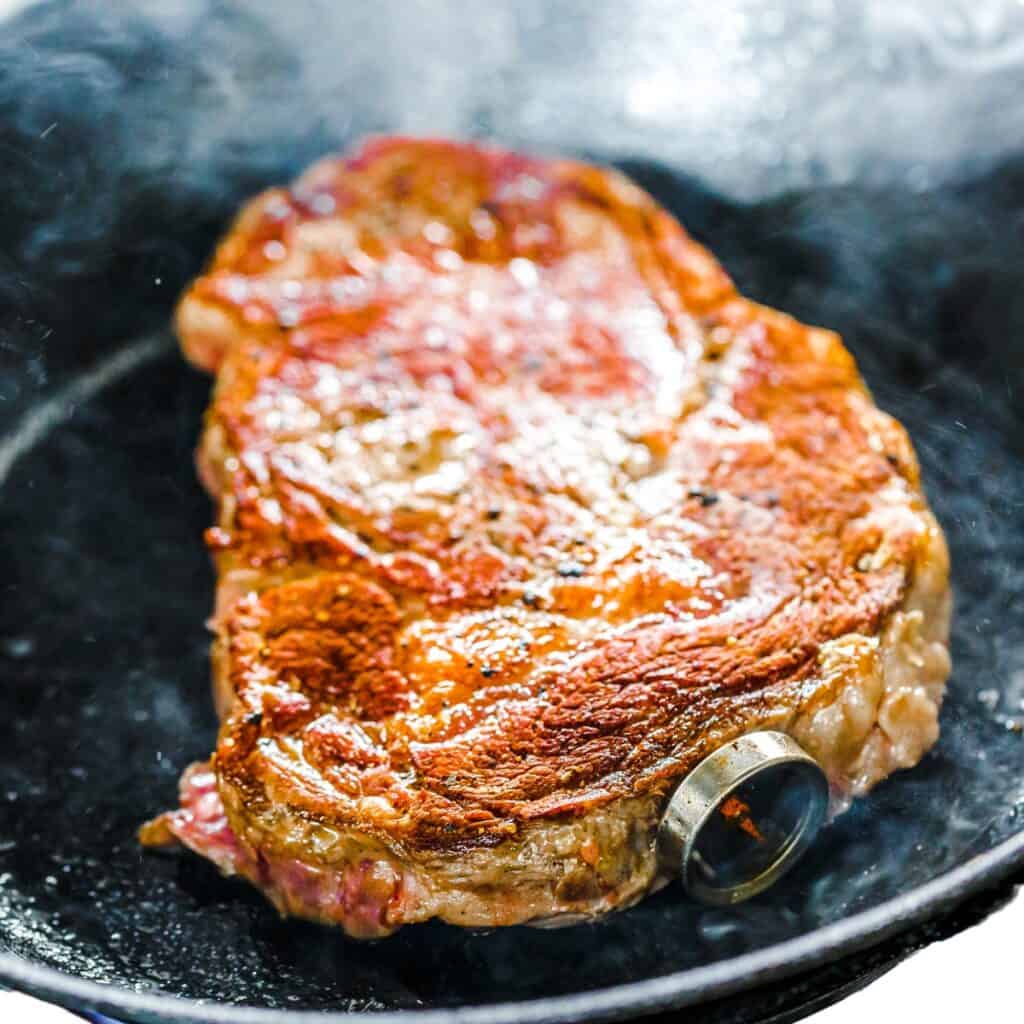 the flipped steak cooing in the pan