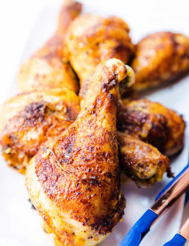 a white platter of baked chicken legs ready to serve