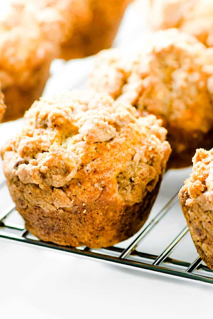 a close up image of Cinnamon Banana Crumb Muffins on a cooling rack