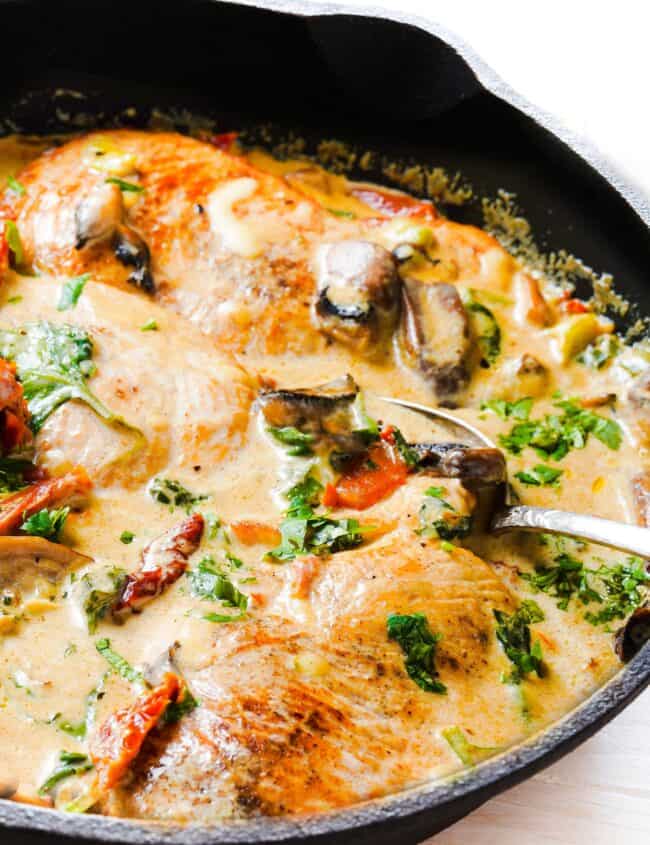 a pan of creamy Tuscan Chicken with mushrooms, spinach and sundried tomatoes