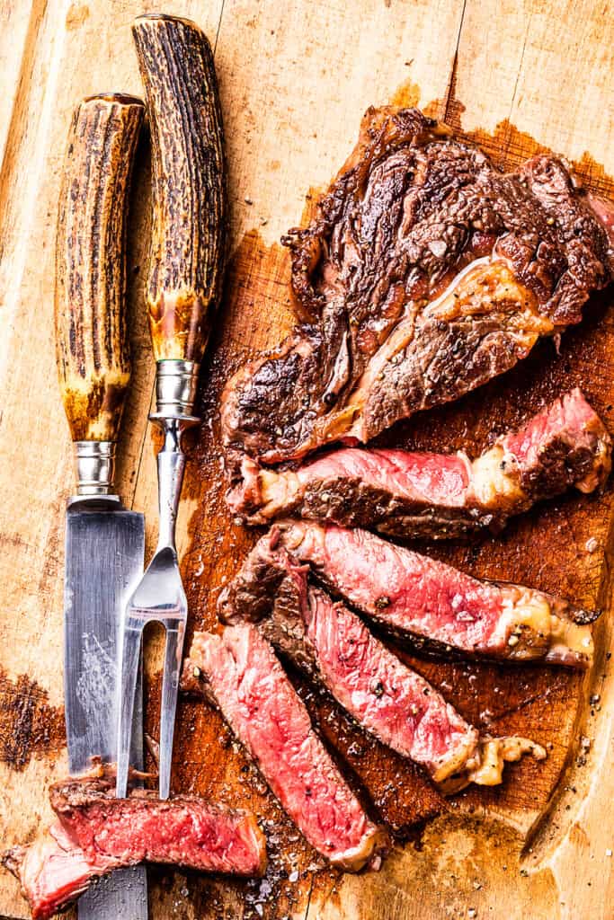 a cutting board with a sliced steak cooked to medium rare