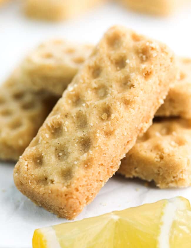 a pile of Lemon Shortbread Cookies stacked around each other with lemon wedges on the table