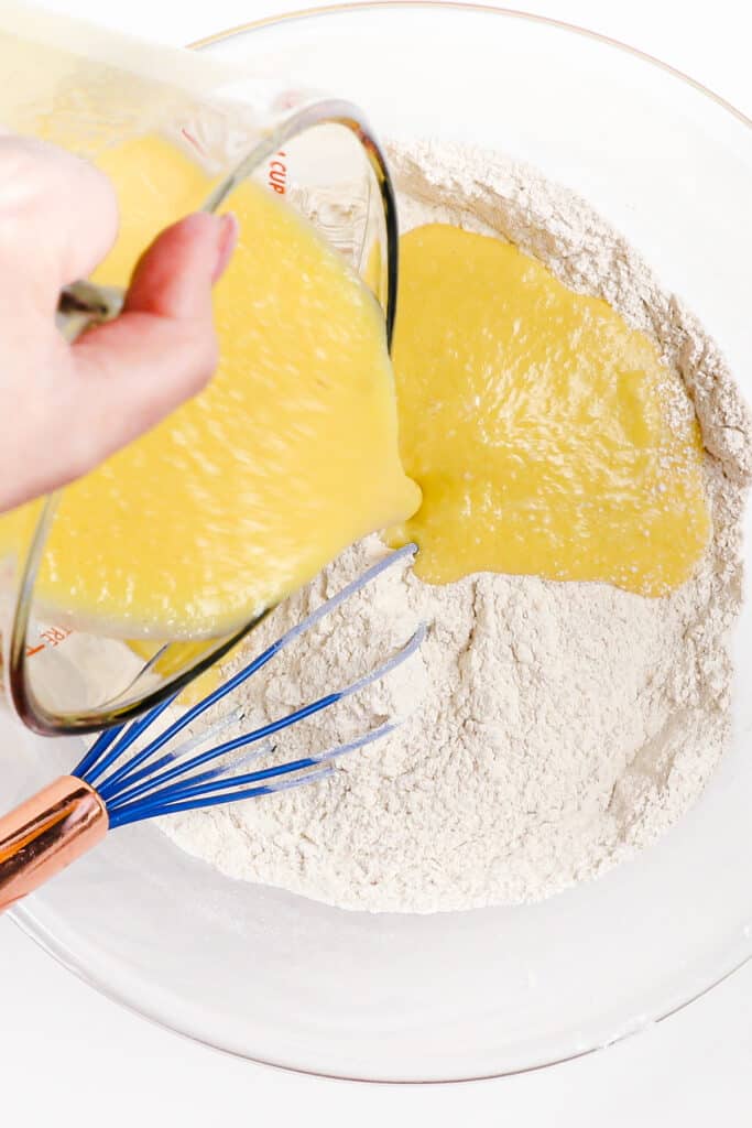the wet ingredients being poured into the bowl with the flour mixture