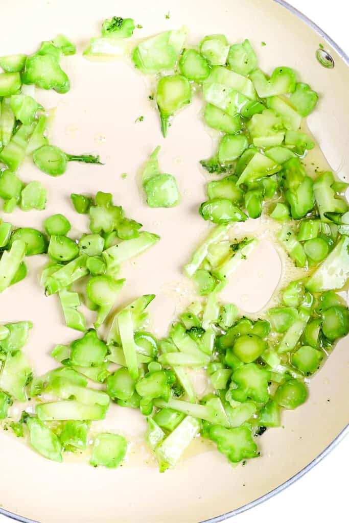 sliced broccoli stems cooking in a pan with olive oil