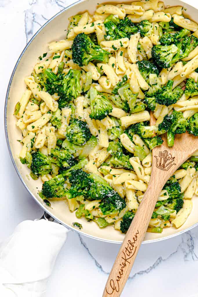 a skillet full of cavatelli and broccoli and a serving spoon in the pan