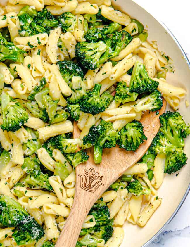 a close up image of a skillet full of cavatelli and broccoli and a serving spoon