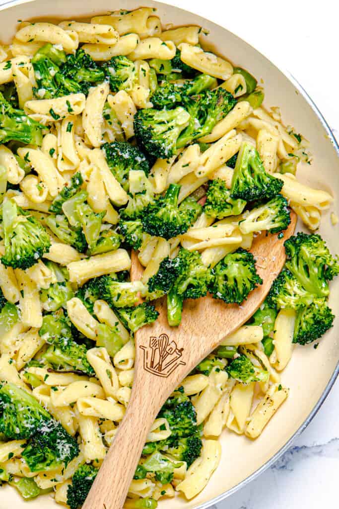 a close up image of a skillet full of cavatelli and broccoli and a serving spoon