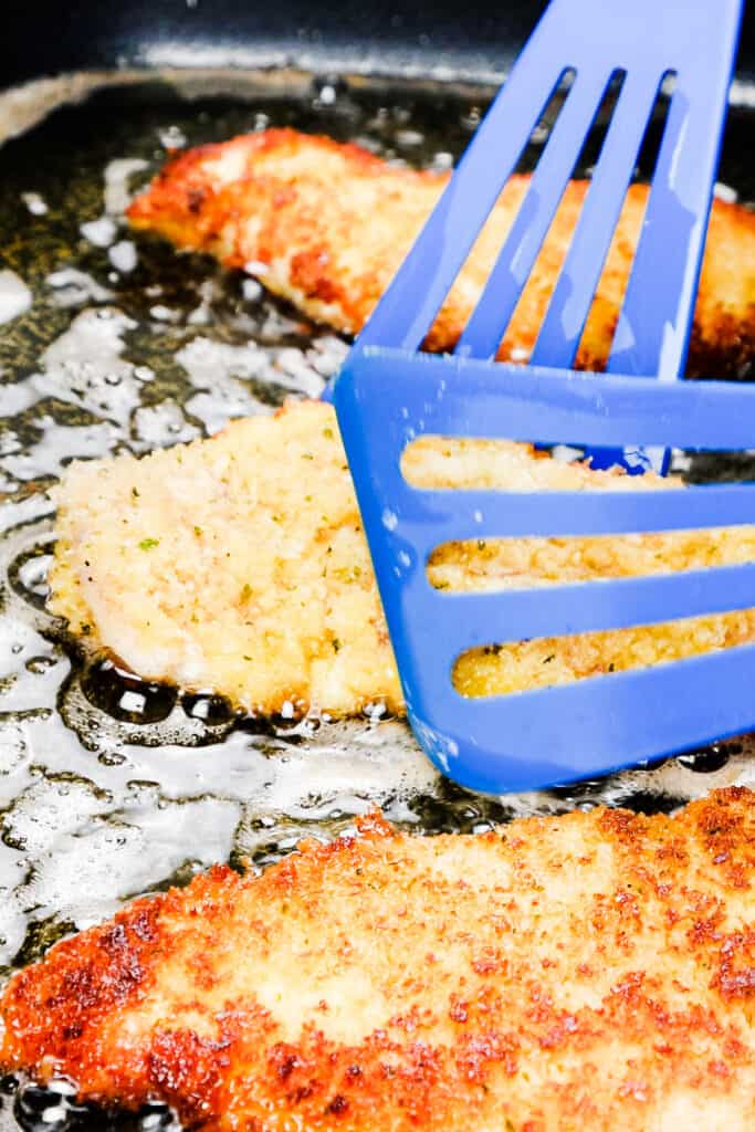 Panko Chicken being flipped in the pan with two spatulas