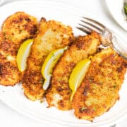 an overhead image of Panko Chicken on a plate with a fork and lemon wedges