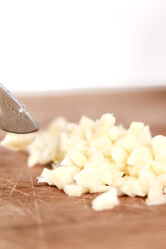 garlic being cut on a chopping board.