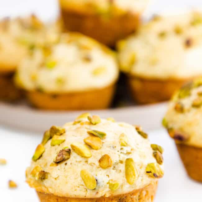 a pistachio muffin topped with chopped pistachios with more in the background