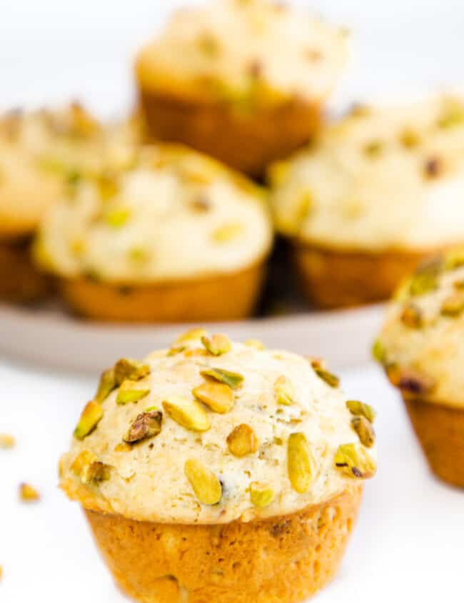a pistachio muffin topped with chopped pistachios with more in the background