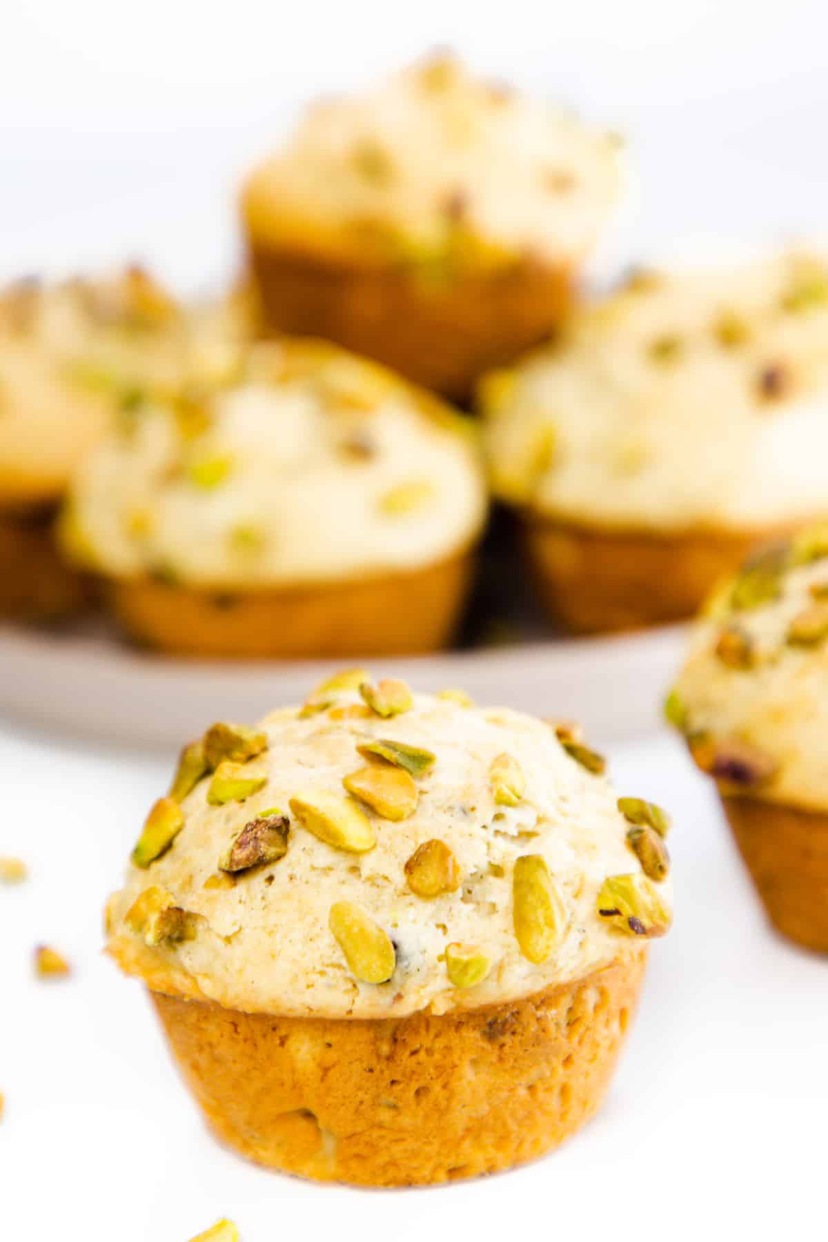 a pistachio muffin topped with chopped pistachios with more in the background
