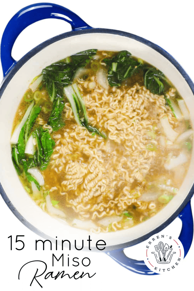 A big pot of miso ramen soup cooking with broth, ramen noodles, and bok choy.