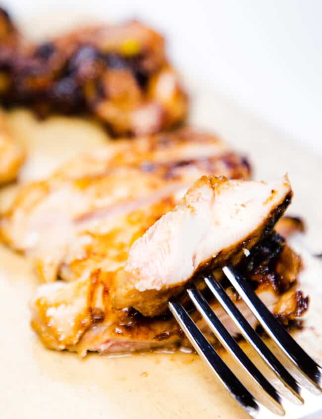 a slice of miso chicken on a fork with more slices in the background