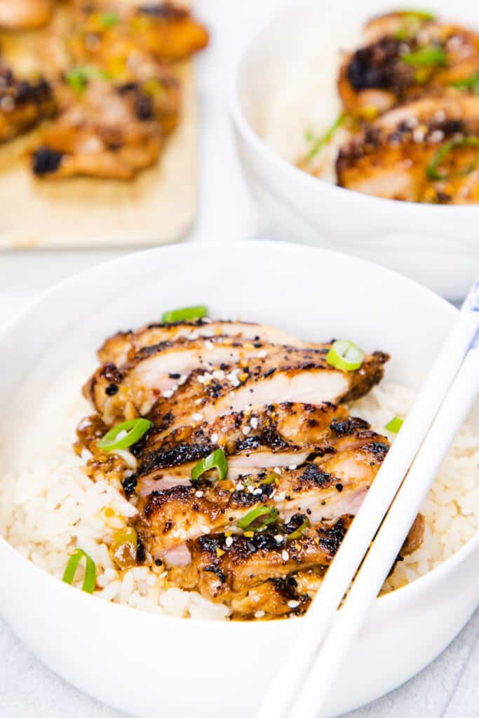 sliced miso chicken in a bowl on top of rice with more in the background