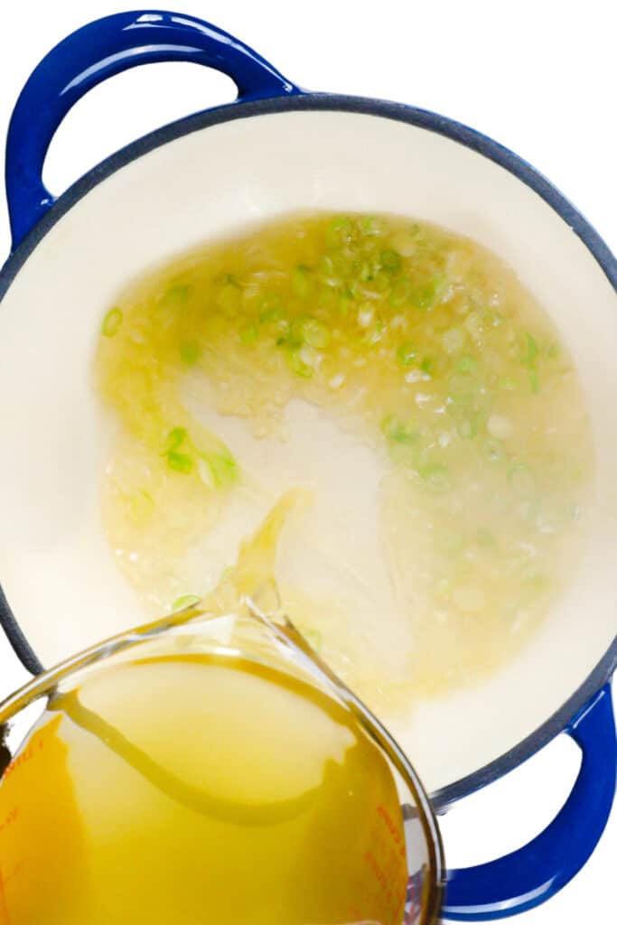 stock pouring into the pot from a glass jug