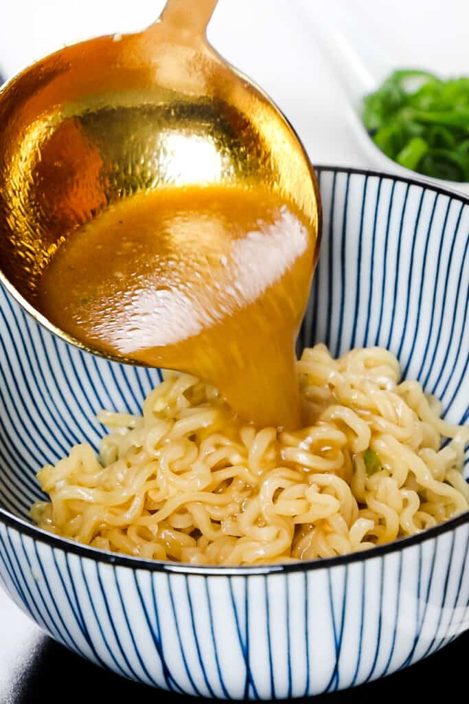 the broth being poured over the noodles in a bowl