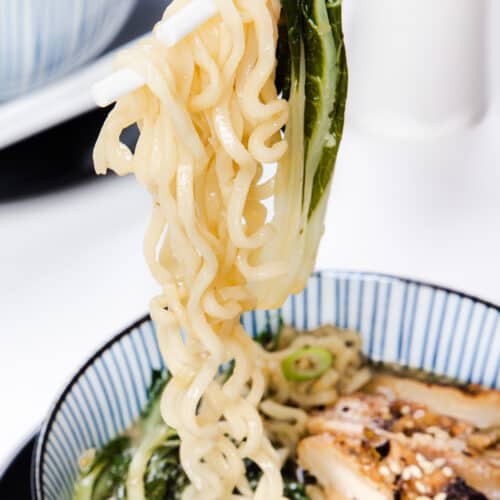 chopsticks holding miso ramen over a bowl