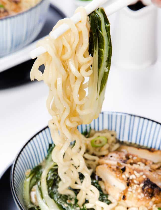 chopsticks holding miso ramen over a bowl