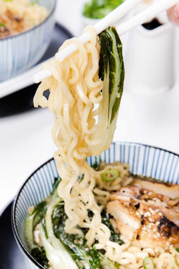 chopsticks holding miso ramen over a bowl