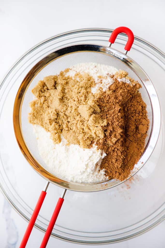 the flour cocoa powder and brown sugar being sifted into a bowl