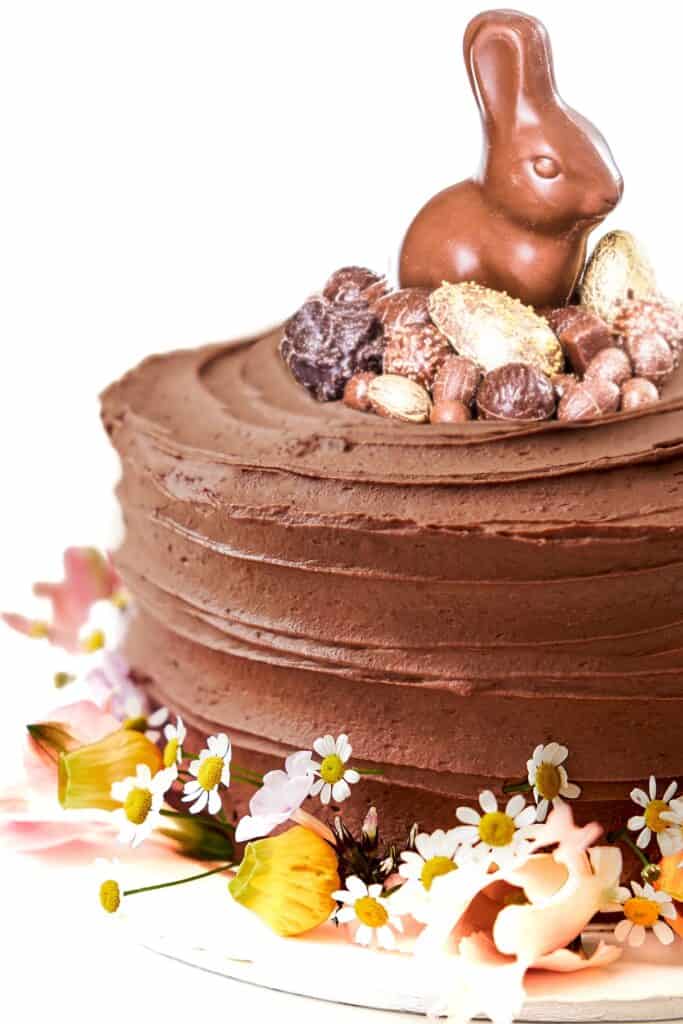 A vertical closeup shot of a chocolate cake decorated with flowers and easter candy