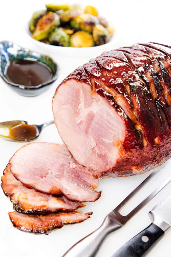 the honey glazed ham on a platter with some slices in front of it