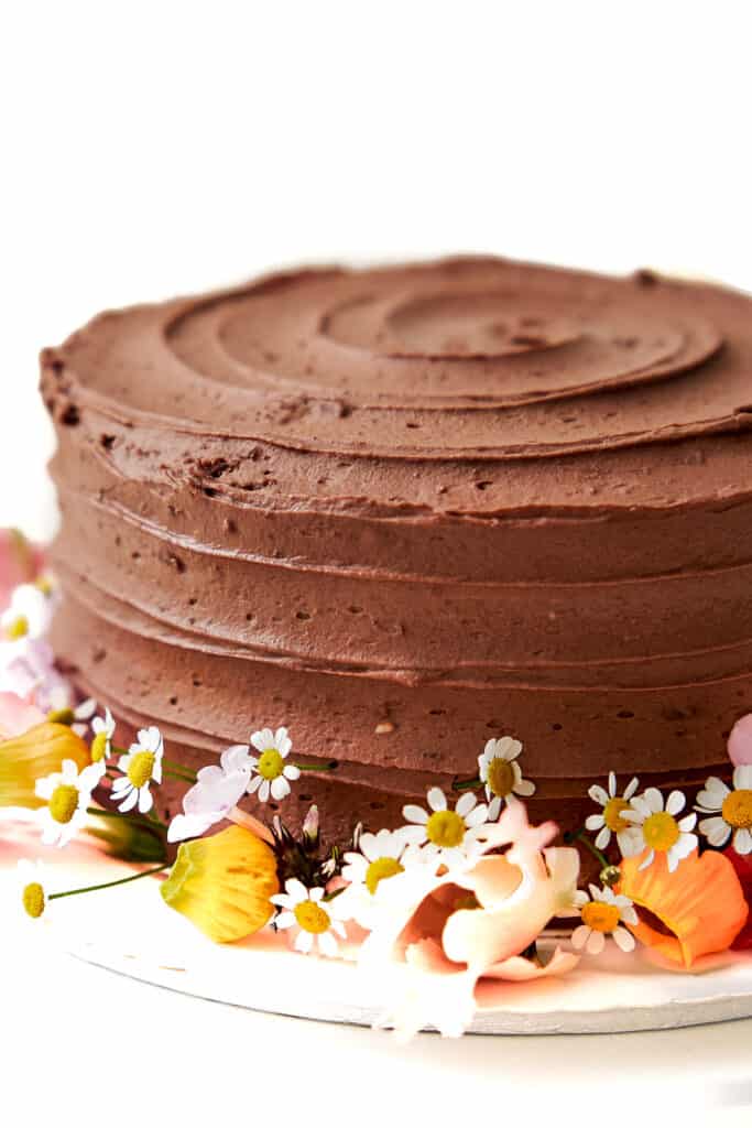 A vertical closeup shot of a chocolate cake decorated with flowers