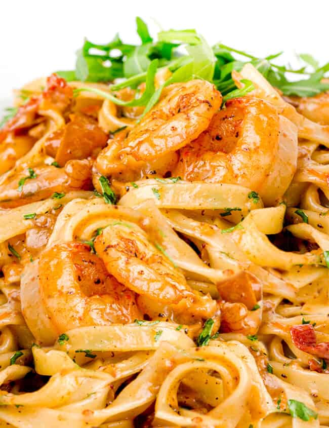 a close up image of of Easy Shrimp Pasta with greens in the background